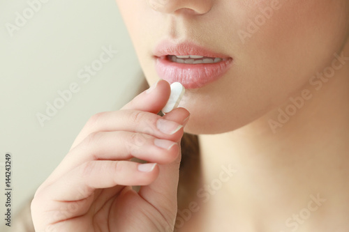 Beautiful young woman taking pill  closeup