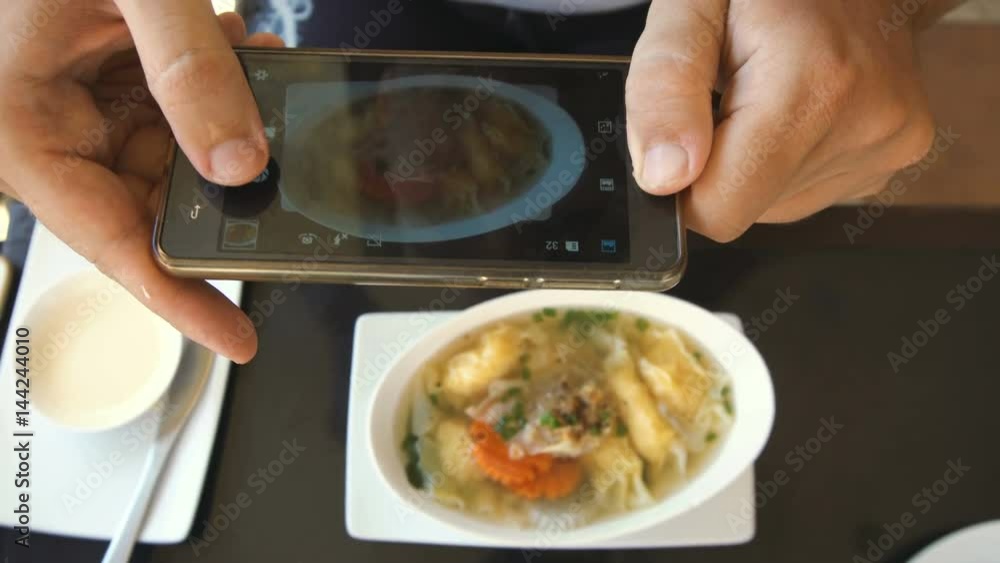 Man Taking Food Photo of Asian Wonton Soup. Asian Cuisine. Social Network Addiction Concept Man Taking Food Photo of Asian Wonton Soup. Asian Cuisine. Social Network Addiction Concept