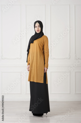 Beautiful Islamic girl in a closed, traditional Muslim dress, a studio photo in full growth