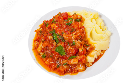 pieces of fish in tomato sauce with mashed potatoes. top view. isolated on white