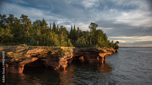 Sea caves with forest and colorful sunset.