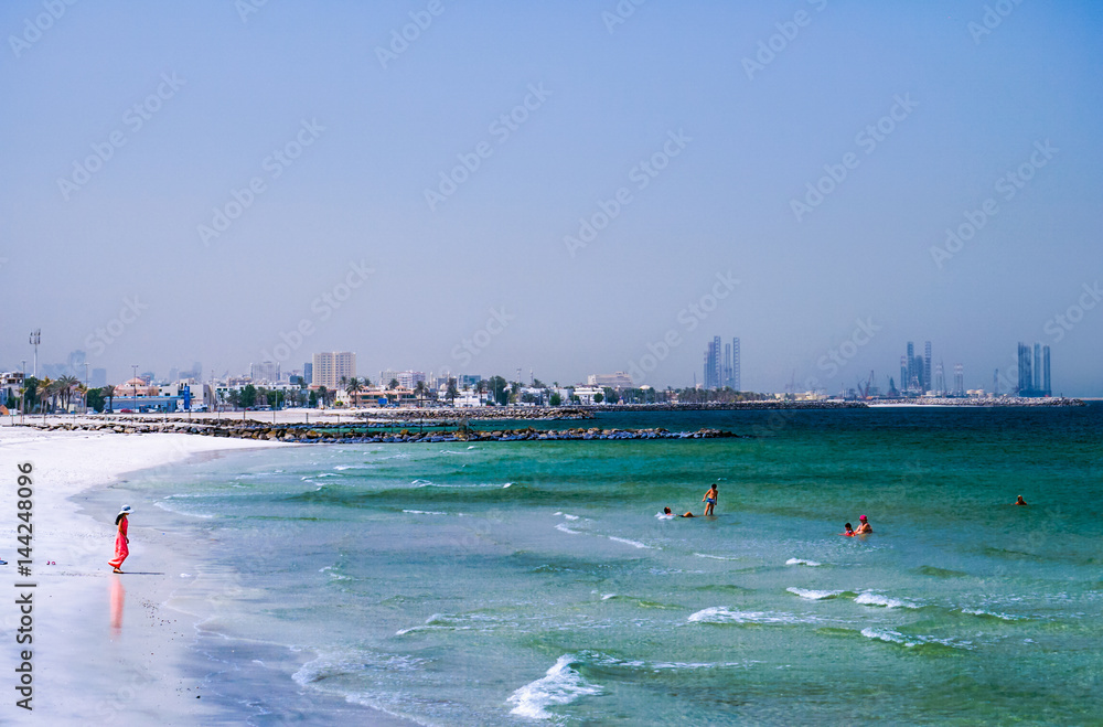 Obraz premium Dubai. Summer 2016. The Persian Gulf with the line of the beach from the Ajman. Woman in red plays on the beach.