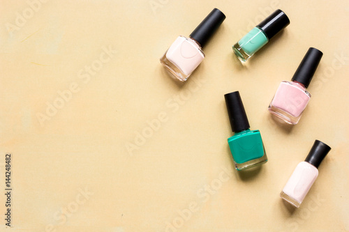collection of nail polish on orange desk background top view mock up