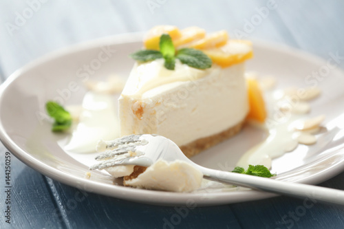 Fork and tasty cheesecake slice with fruit on plate
