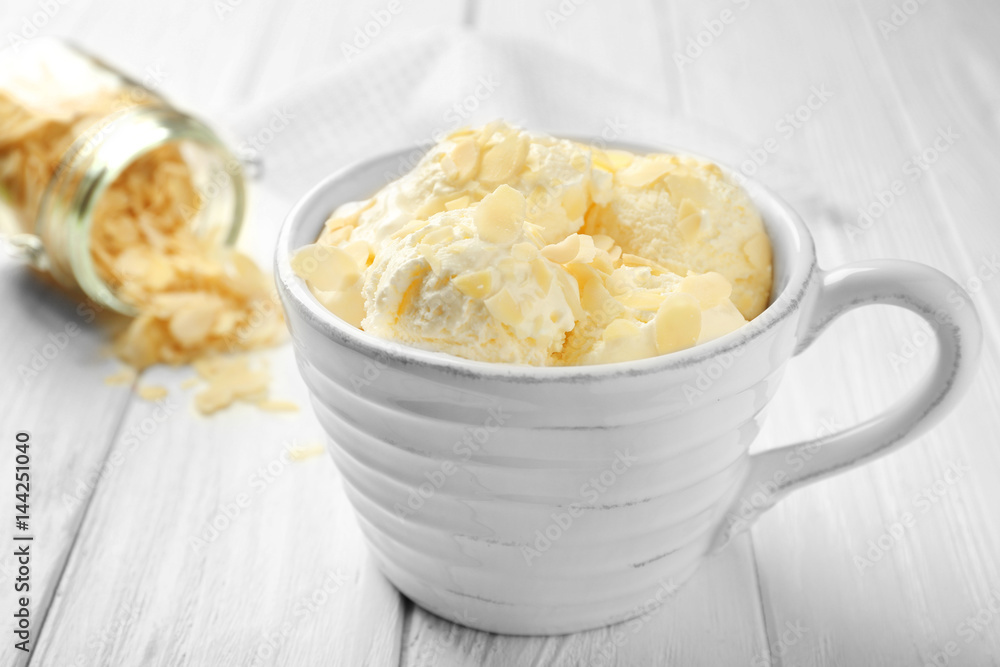 Tasty ice-cream with almond slices in cup on wooden background Tasty ice-cream with almond slices in cup on wooden background