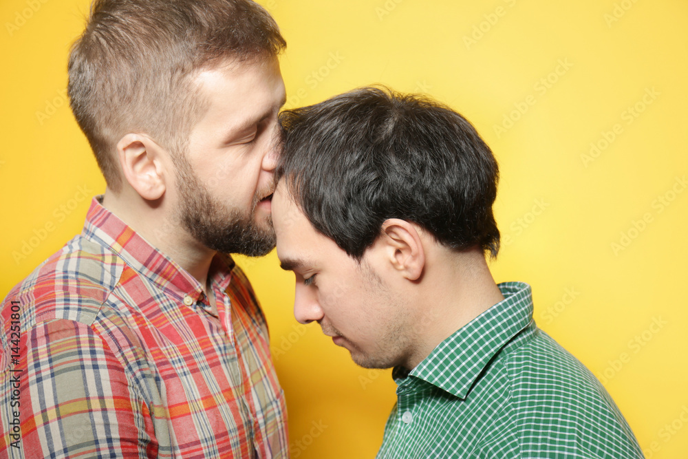 Happy gay couple posing on yellow background Happy gay couple posing on yellow background