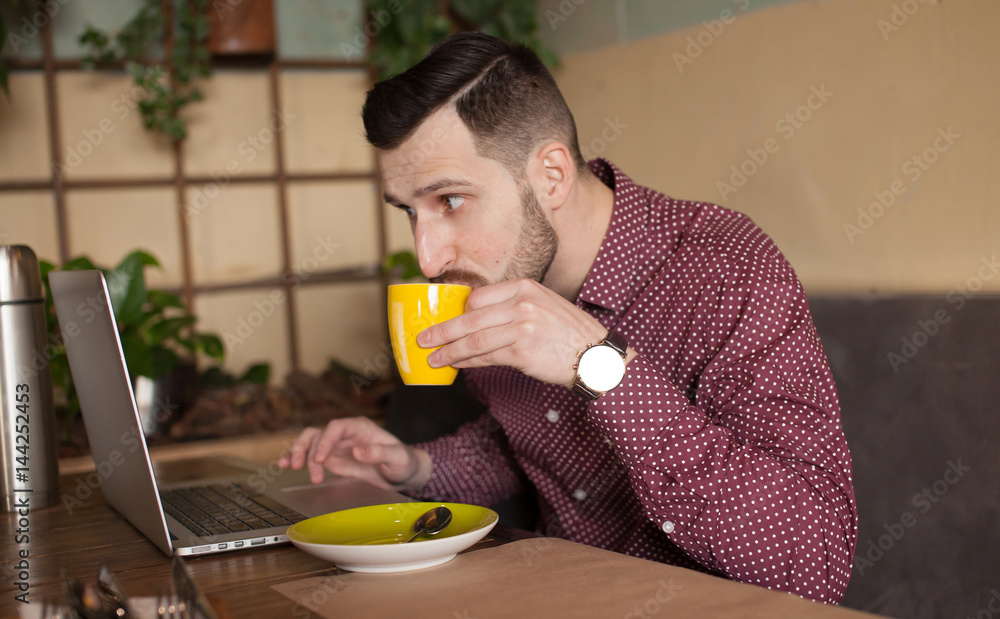 Shot of a young businessman working on his laptop in a cafe shop. Selective focus. Shot of a young businessman working on his laptop in a cafe shop. Selective focus.