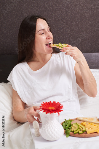 Happy woman in pajamas eats healthy breakfast
