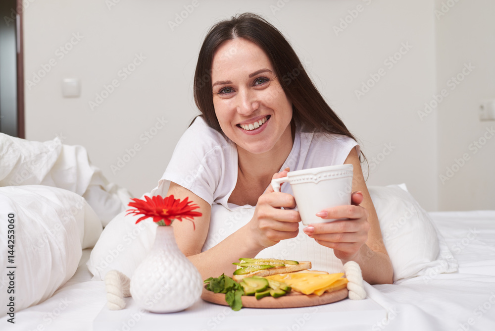 Brunette with charming smile enjoying cup of tea