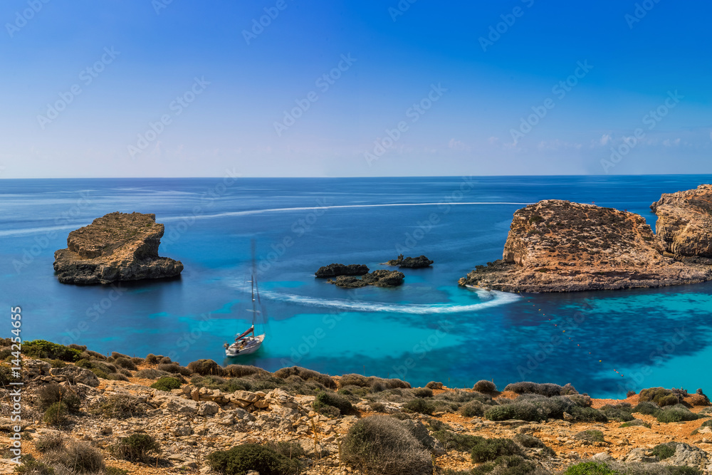 Comino, Malta - Panoramic skyline view of the  beautiful Blue Lagoon on the island of Comino with sailboats and tourists enjoying the mediterranean sea
