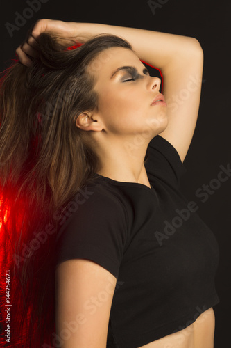 Perfect brunette woman with art makeup at studio with red light
