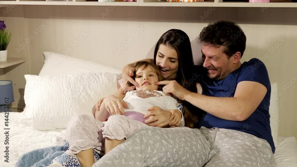 Happy family having fun watching television in bed using remote control medium shot