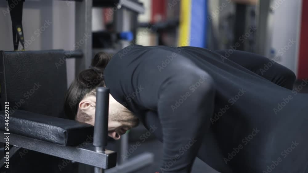 Close up of a bearded young man wearing black sportswear doing push ups on a machine in a gym. Handheld real time close up shot. Close up of a bearded young man wearing black sportswear doing push ups on a machine in a gym. Handheld real time close up shot.