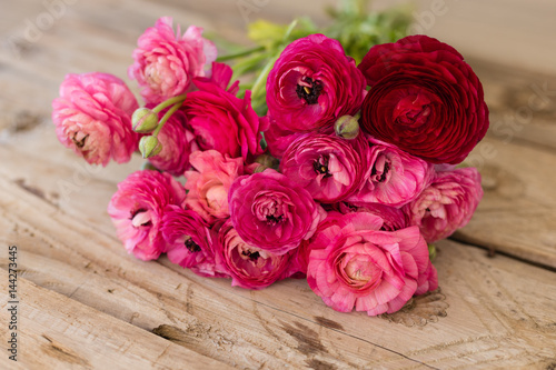 Bouquet of pink ranunculus lying on rustic tabletop