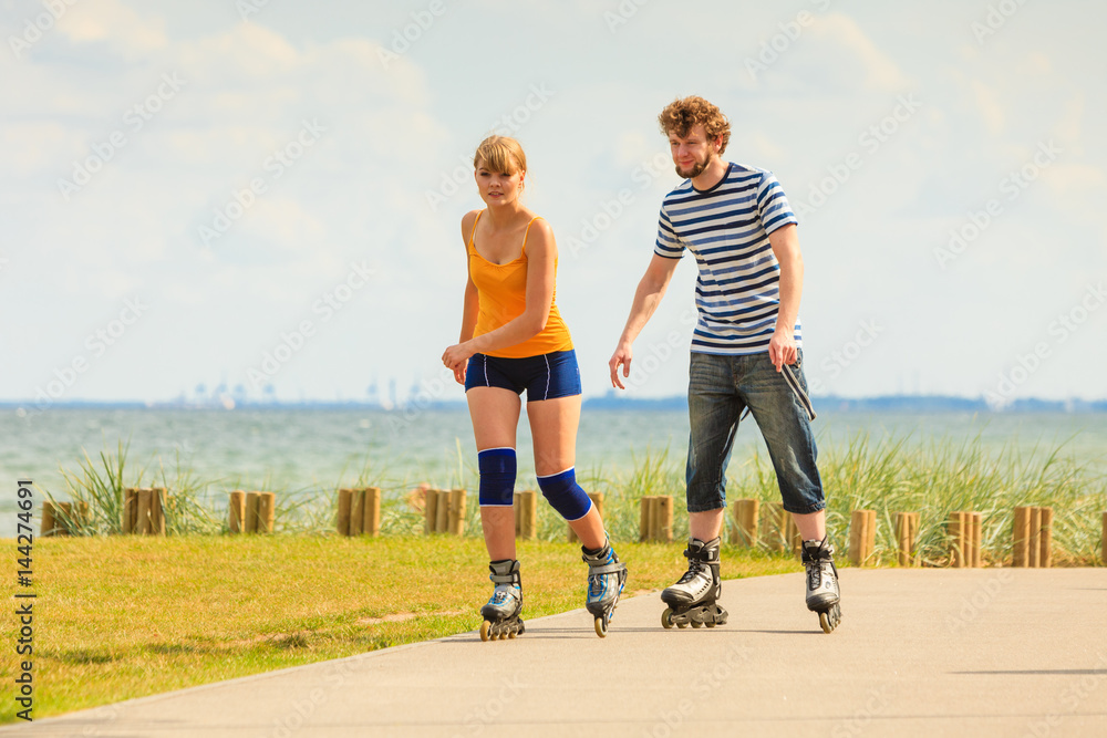 Fototapeta premium Young couple on roller skates riding outdoors
