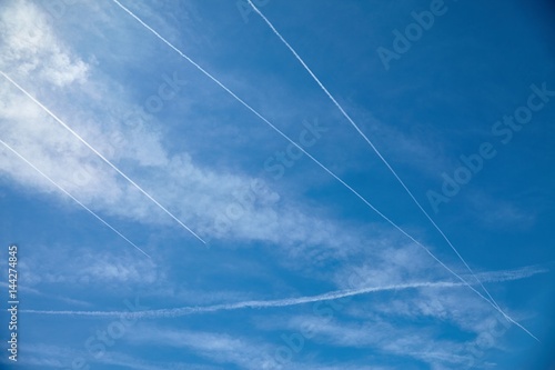 Airplanes flying in the blue sky among clouds and sunlight