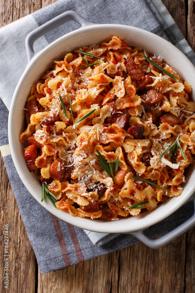 farfaline pasta with tomato, bacon and Parmesan close-up in a saucepan. Vertical top view farfaline pasta with tomato, bacon and Parmesan close-up in a saucepan. Vertical top view