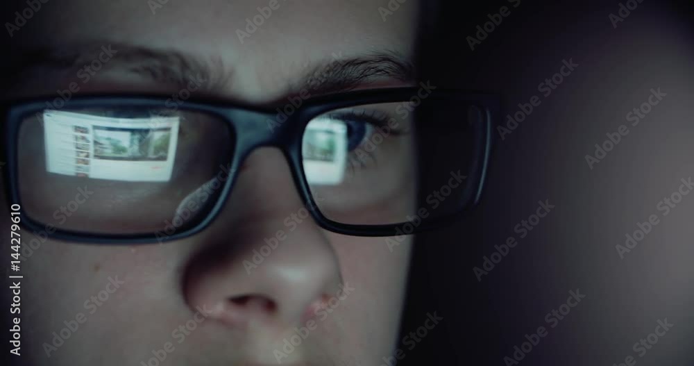 12 years teen puberty eye glasses looking at the monitor in a dark room,surfing the Internet, close-up 12 years teen puberty eye glasses looking at the monitor in a dark room,surfing the Internet, close-up