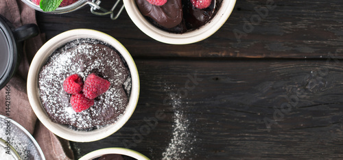 Chocolate cakes with berries on the wooden background with border