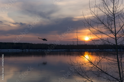 Mi-8 helicopter flying over the river. Sunset with a flying Mi-8 helicopter.