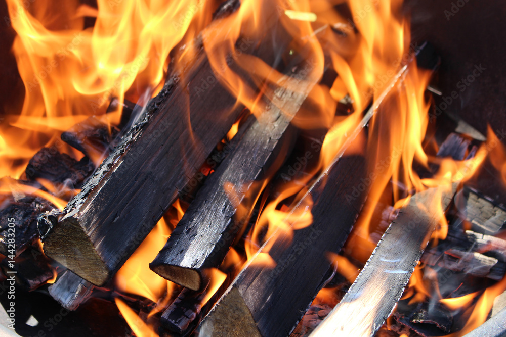 Charred wood and bright flames on dark background Charred wood and bright flames on dark background