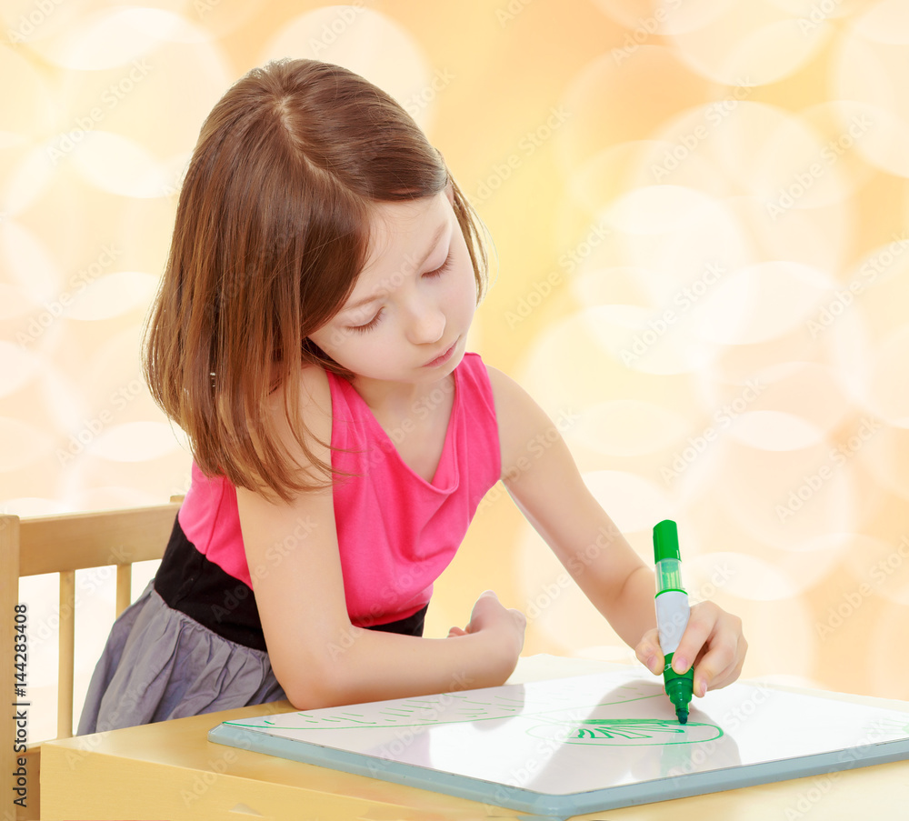 little girl draws with marker sitting at the table. little girl draws with marker sitting at the table.