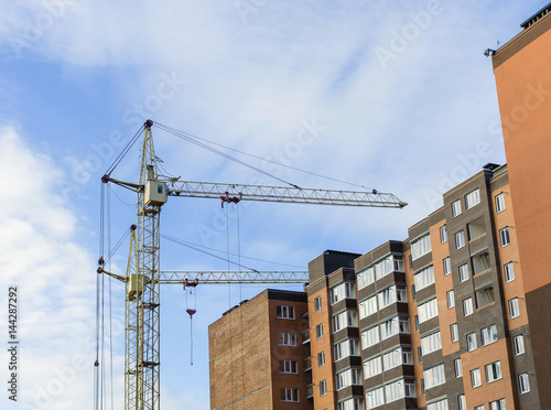 Building and construction work. Construction crane against blue sky.