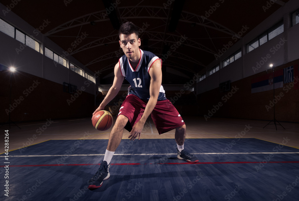 Fototapeta premium basketball player dribbling ball thought the legs