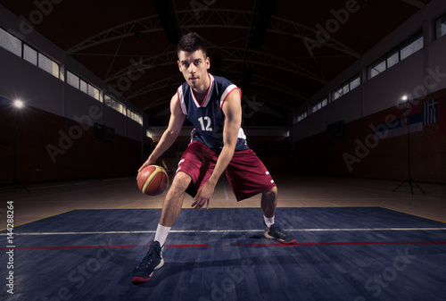 basketball player dribbling ball thought the legs