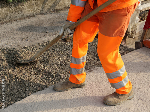 worker with the shovel adjacent at trench in the roadwork