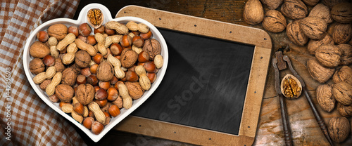 Dried fruits in a bowl in the shape of a heart on a table with a blackboard - Healthy eating