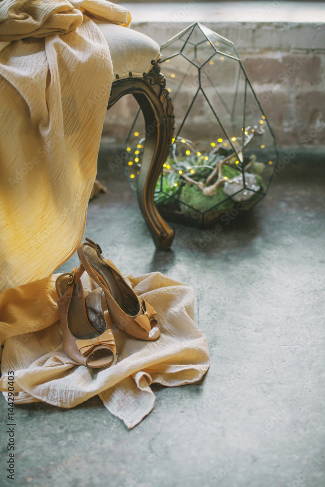 Bride`s boidoir, details of her peignoir and shoes on a chair, loft studio