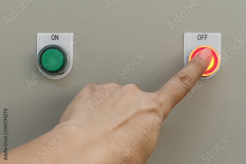 Forefinger touch on red off button for machine control.
