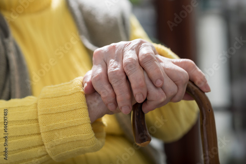 Old woman hands holding a cane