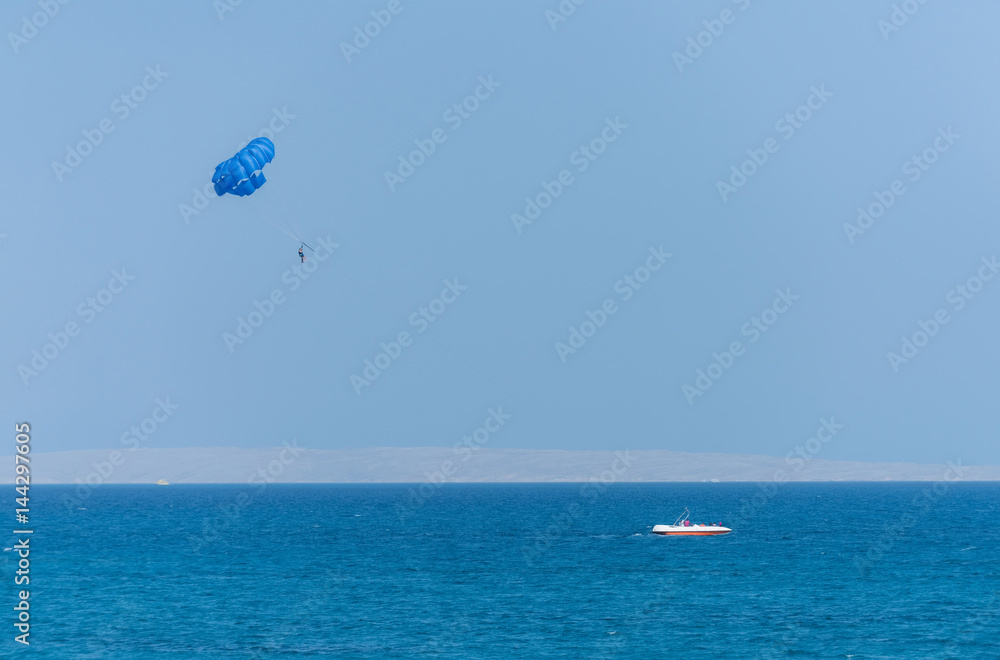 Idyllic blue sea with motor boat and parachute parasailing Idyllic blue sea with motor boat and parachute parasailing