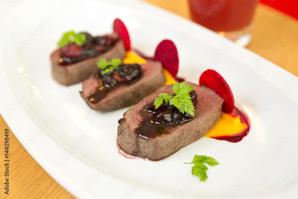 Organic Venison served with fresh raspberry raspberry sauce, beetroot slices and pumpkin puree, on a white plate. Organic Venison served with fresh raspberry raspberry sauce, beetroot slices and pumpkin puree, on a white plate.
