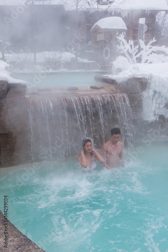 Ethnic couple relaxes in outdoor spa during winter