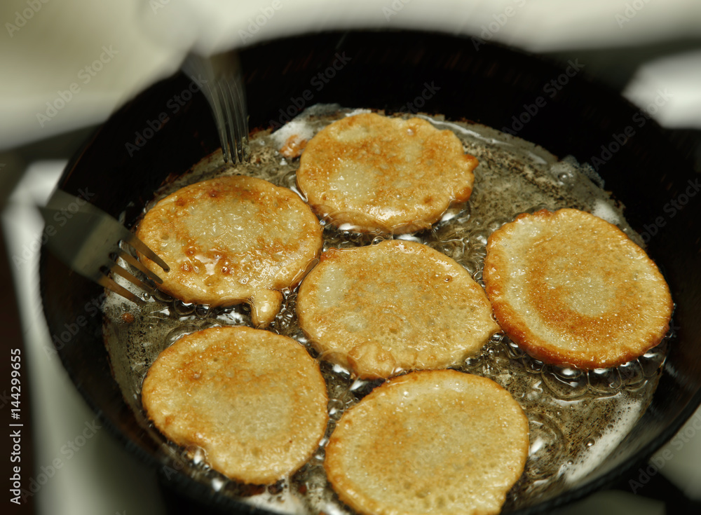 Cooking process of potato flapjacks on the pan with boiling sunflower oil close up with motion blur Cooking process of potato flapjacks on the pan with boiling sunflower oil close up with motion blur