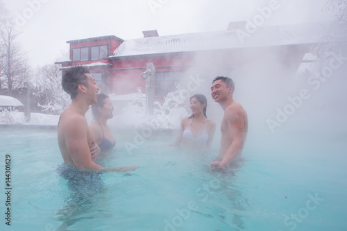 Obraz na płótnie Ethnic couples relax in outdoor spa during winter w salonie