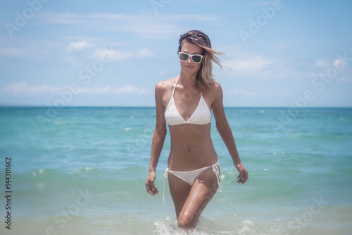 Beautiful young woman in a white bikini on a beautiful paradise sea beach