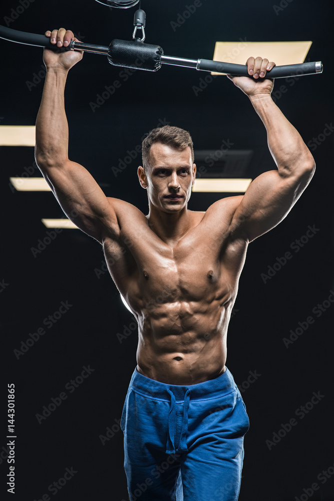 Handsome man with big muscles, posing at the camera in the gym Handsome man with big muscles, posing at the camera in the gym