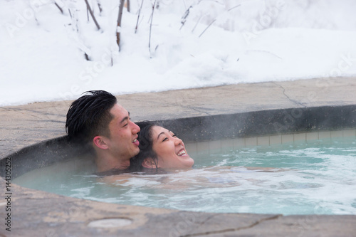 Obraz na płótnie Ethnic couple relaxes in outdoor spa during winter w salonie
