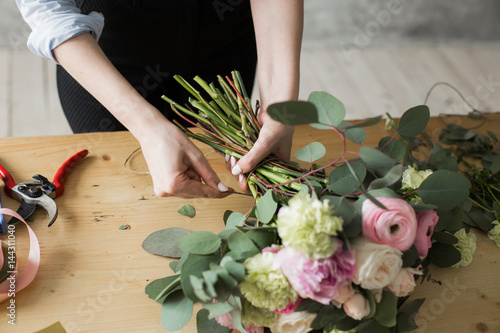 Florist at work: pretty young woman making fashion modern bouquet of different flowers photo
