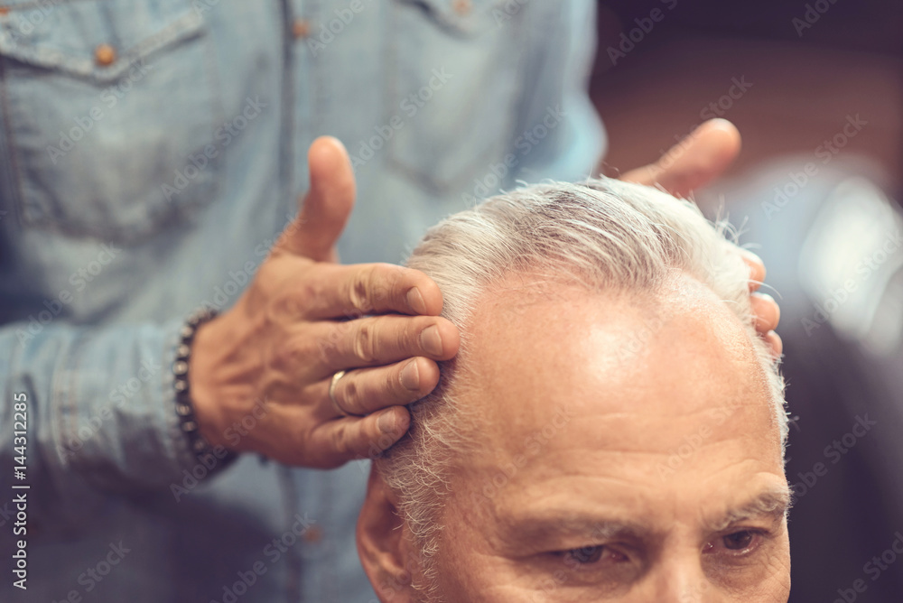 Obraz premium Proficient hairdresser styling hairdo of the client in the salon