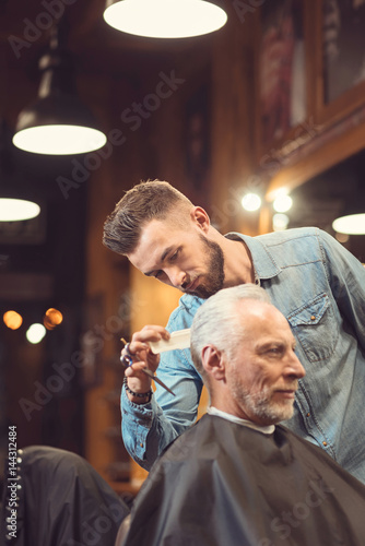 Brutal hairdresser combing haircut of the client in the salon