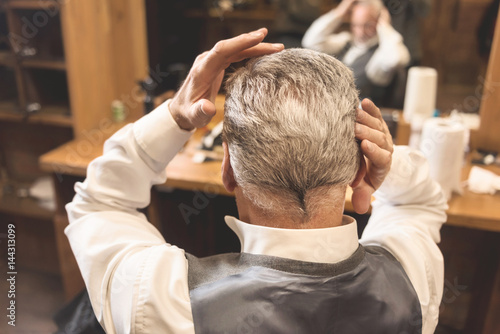 Aged businessman looking at his new haircut in the mirror