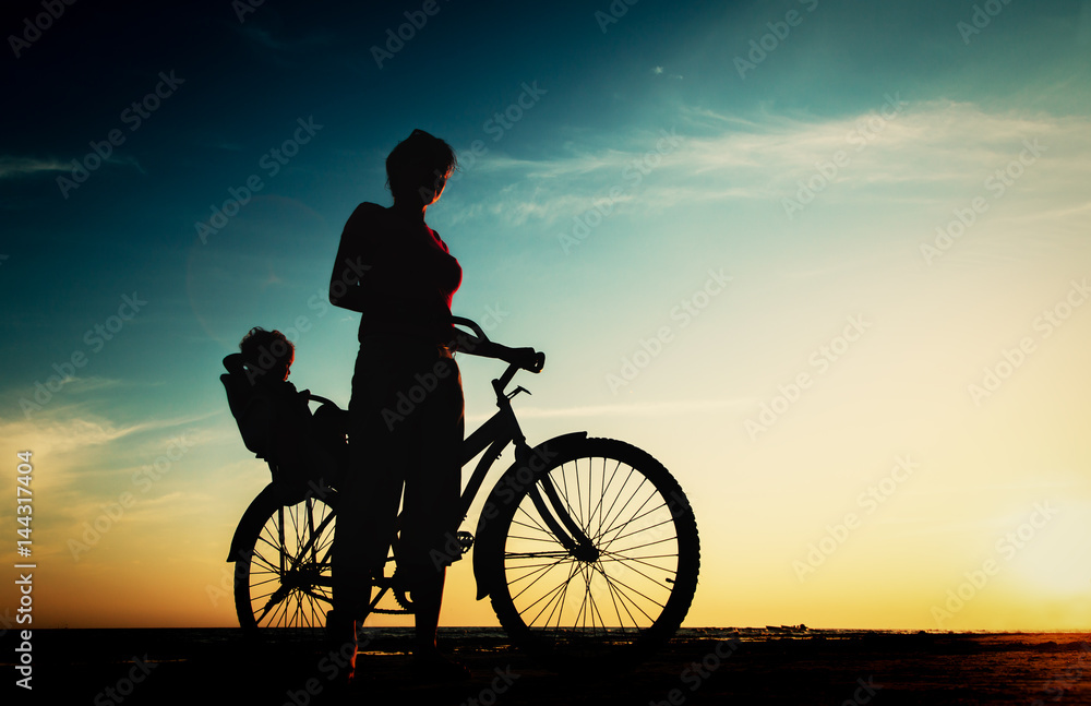 Fototapeta premium Silhouette of mother and baby biking at sunset