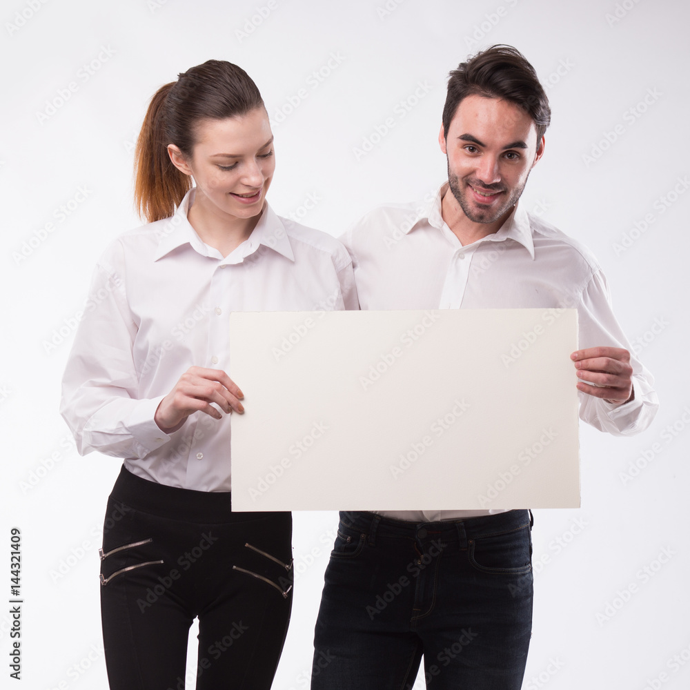 Young happy couple showing presentation pointing on placard over gray background Young happy couple showing presentation pointing on placard over gray background