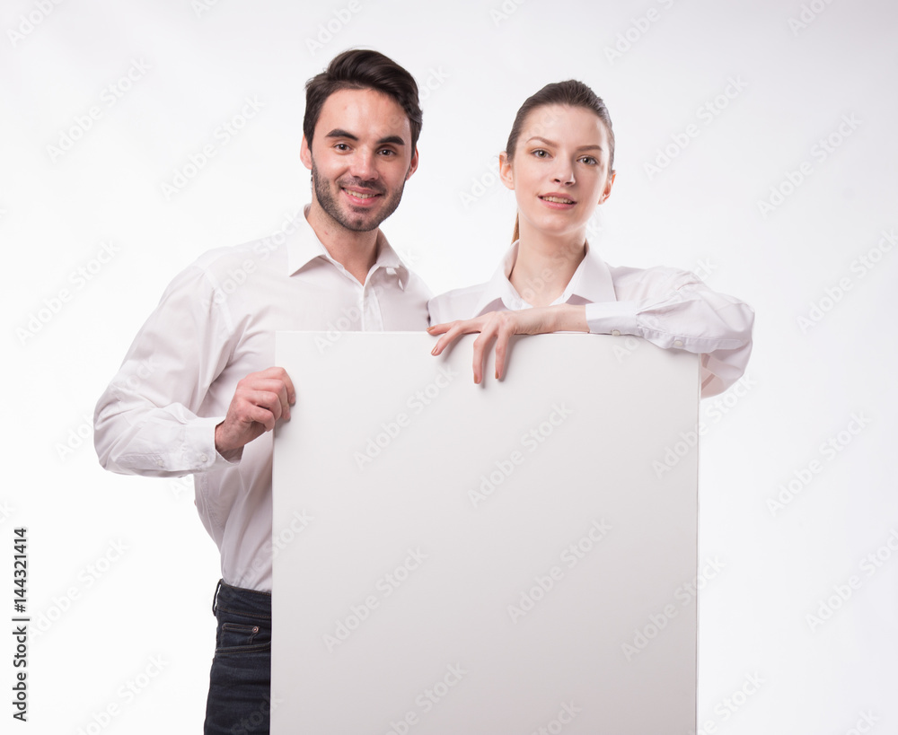 Young happy couple showing presentation pointing on placard over gray background Young happy couple showing presentation pointing on placard over gray background