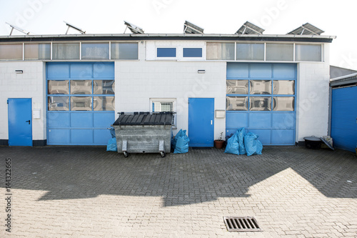 Gewerbehof mit blauen Toren und Müllcontainer